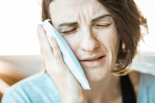Woman holds an ice pack to her cheek