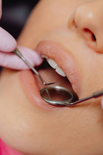 dental exam mirror probe A dentist examining a patient's mouth using a small circular mirror and a metal probe