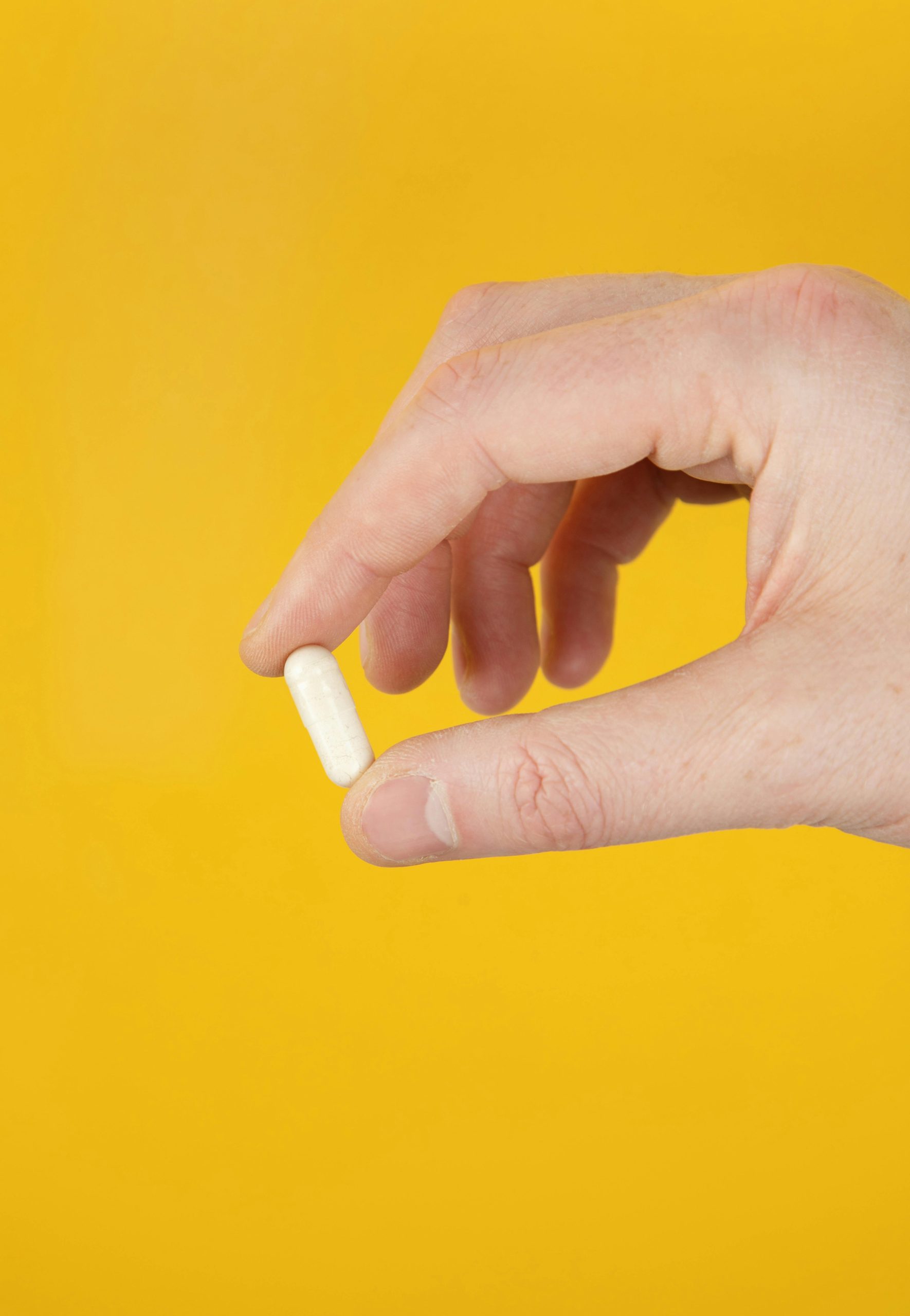 hand holding white capsule pill Hand holding a white capsule pill