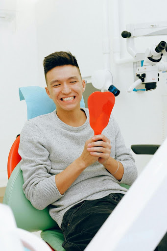Man smiles holding dental mirror