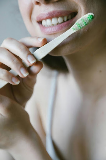 A woman smiling holding a bamboo toothbrush