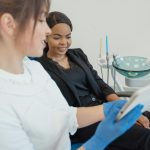 A dentist showing dental treatment plan on a tablet to a female patient