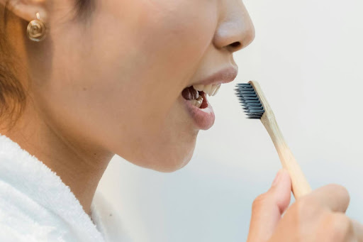 A woman brushing her teeth with a bamboo toothbrush