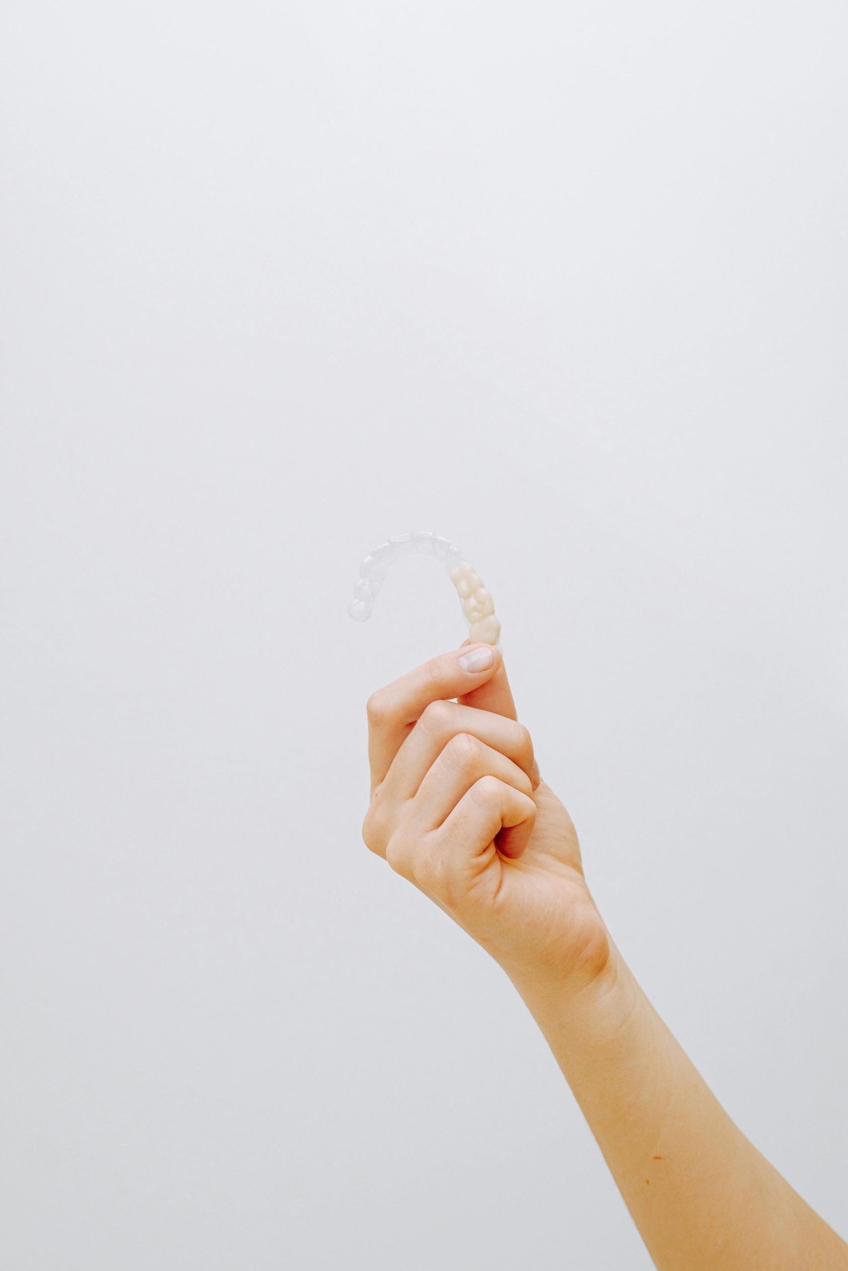 A hand holding a clear dental aligner