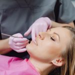 Dentist using a dental instrument to examine a female patient's teeth