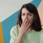 Woman covering her mouth due to bad breath